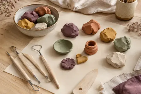 Portions d’argile autodurcissante colorée et outils de sculpture sur une table d’atelier claire