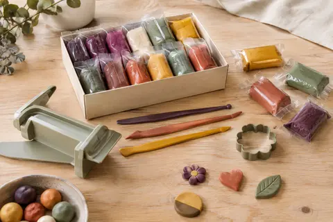 Pâte autodurcissante multicolore avec presse à plaque, outils et formes modelées sur une table d’atelier
