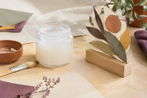 Pot de vernis-colle mat transparent posé près de papier décoré et d’un support en bois