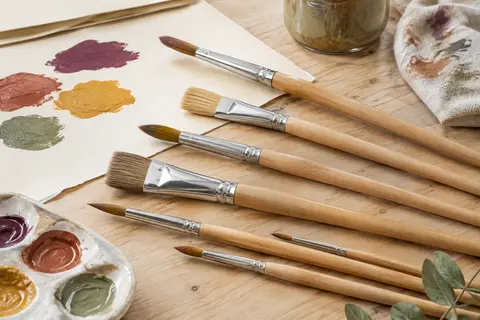 Assortiment de pinceaux ronds et plats K3T à manches en bois naturel posé sur une table d’atelier claire.