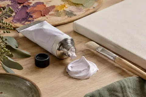 Tube de peinture acrylique épaisse posé près d’une touche Orchidée blanche et d’un pinceau