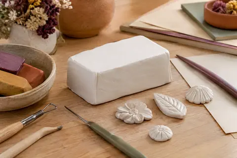 Bloc d’argile polymère blanche et formes décoratives sur une table d’atelier en bois clair.