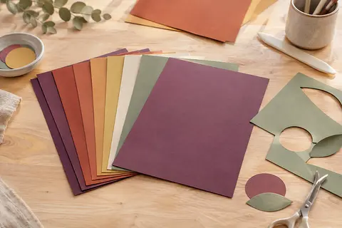 Feuilles de papier cartonné A4 de différentes couleurs disposées sur une table d’atelier en bois clair